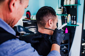 hands of mexican man stylist cutting hair to a client in a barber shop in Mexico