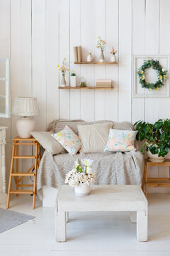 Decorative zone with tender flowers on a vintage white table in interior. Tender room in white colors. Living room in rustic style