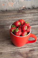 Fresh organic strawberry in red cup on wooden background. Healthy breakfast. Natural farming. Growing fruit. 