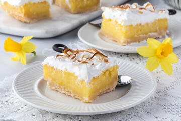 Close up of a serving of lemon meringue squares with other slices in behind.