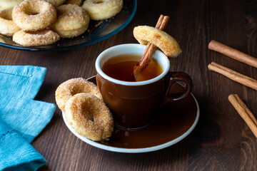 Close up of a cup of tea with sugar cinnamon mini donuts against a dark background.