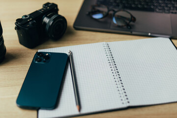 Modern white office desk table with laptop, smartphone and other supplies. Blank notebook page for...