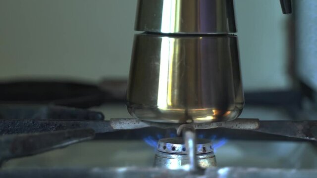 male hand hand with a burning match sets fire to a gas burner with a geyser coffee maker, moka pot. Extreme Close-Up, camera movement from left to right, full HD.