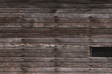 Weathered wooden slats on a wall of an old and abandoned barn
