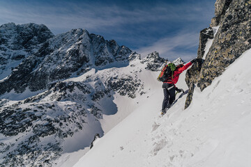 An alpinist climbing in winter alpine like landscape of High Tatras, Slovakia. Winter mountaineering in snow, ice and rock. Alpinism, high peaks and summits with snow and ice.