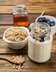 Yogurt, granola, bluberry and honey over wooden table