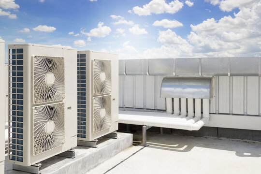 Condenser unit or compressor on roof of industrial plant building with sky background. Unit of central air conditioner (AC) or heating ventilation air conditioning system (HVAC). Pump and fan inside.