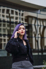 Fototapeta premium Young woman with purple hair talking on cell phone