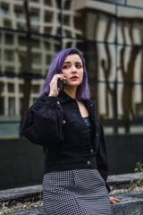 Fototapeta premium Young woman with purple hair talking on cell phone