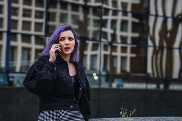 Fototapeta premium Young woman with purple hair talking on cell phone