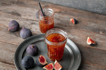 Jars of sweet fig jam on wooden table