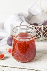 Jar of sweet fig jam on white wooden table
