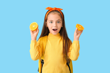 Surprised little girl with orange on color background