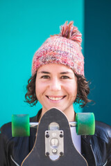 brunette woman with cap and skateboard on colorful background