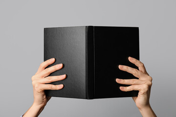 Woman holding open book on grey background, closeup