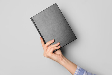 Woman holding book on grey background