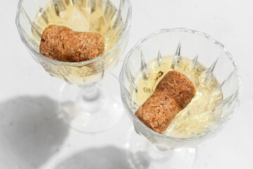 Glasses with champagne and corks on light background, closeup