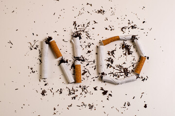 Word Not written with pieces of broken cigarettes, on a white surface.