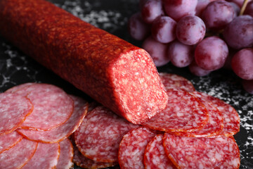Tray with tasty salami and grapes, closeup