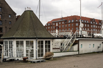 A large boat moored on the canal next to the pavement and historic buildings in Copenhagen