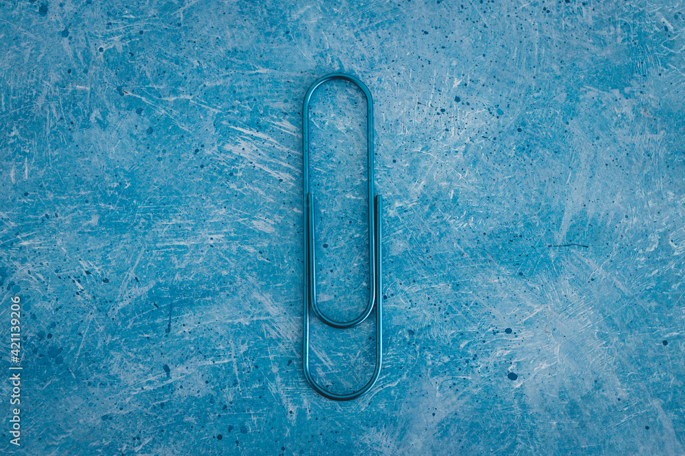 Wall mural flatlay of blue paper clips on abstract blue texture.