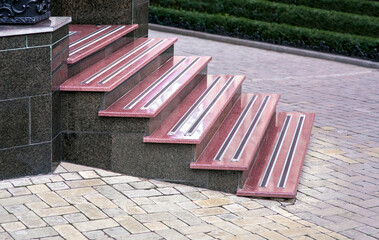 granite staircase with marble steps and non-slip rubber strips near a pedestrian walkway with a...