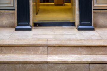 beige marble threshold with steps at the entrance to the glass door of an expensive store with...