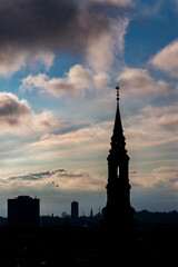 Fototapeta premium Cityscape, amazing silhouettes view over the city of Copenhagen, Denmark. Winter cloudy dark moody picturesque scene. Picture taken from Round Tower. Church tower