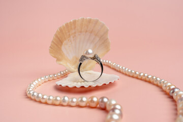 Luxury accessories. Ring with pearls in a shell on a pink background. Pearl necklace. 
Present for...