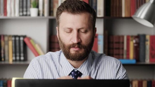 Headache. Upset tired man at workplace, he closes his eyes and touches temporal part and eye area with his hands. Slow motion