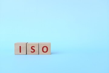 ISO acronym or International Organization for Standardization on wooden blocks in blue background.