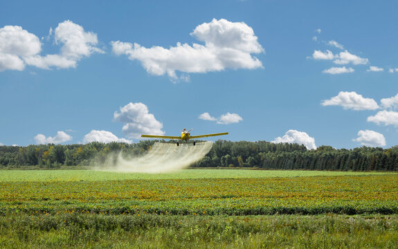 crop duster spraying a farm field pesticide.