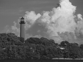 Vintage black and white image of Jupiter Lighthouse and big sky, clouds over inlet