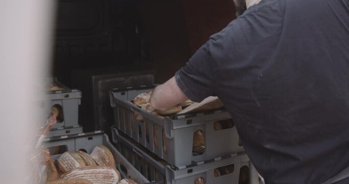 Male baker putting freshly baked ciabatta bread in delivery van