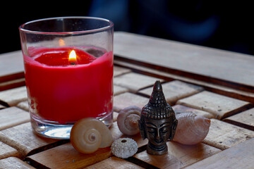 Vela encendida con caracoles de mar y un buda.
