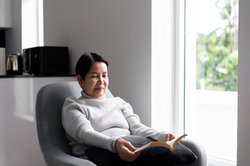 Elderly asian woman reading a book at home,Relax time,Senior lifestyle concept,Long sighted