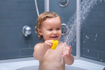 Baby child washing in a bathroom in foam. Child in shower.