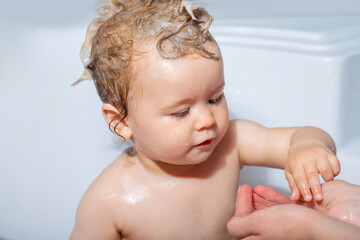Child bathing. Baby showering. Portrait of kid bathing in a bath with foam.
