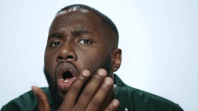 Portrait of handsome african american man checking beard in light background.