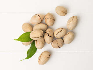 Top view of unpeeled pecans scattered on a white wooden table.