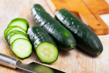 Ripe cucumbers and knife on wooden cutting board. High quality photo