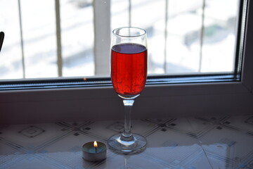 A glass of red wine and a burning candle.