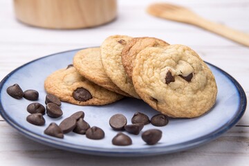 Close up of a plate of delicious chocolate chip cookies and scattered chocolate chips. Photographed...