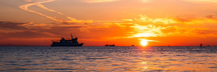 Fototapeta na wymiar Beautiful sunset on the sea coast. The sun reflecting on the sea. Nature background. Banner.