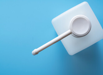 Bottle of alcohol sanitizer spray placed on a blue background in copy space.