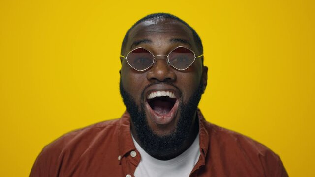 Portrait of surprised african american man posing on yellow background. 