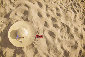 Fototapeta na wymiar BEACH PARAPHERNALIA ON THE SAND: SUNGLASSES, HAT. TRAVEL TO THE SEA