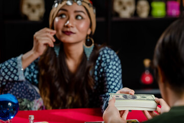 Fototapeta premium Confident Asian sorceress taking money from customer