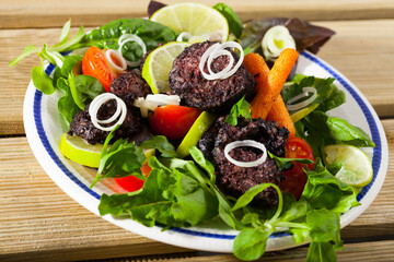 Black pudding with rice served with vegetables, lime and herbs