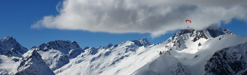 Paragliding in the snow mountains in calm sunny weather.